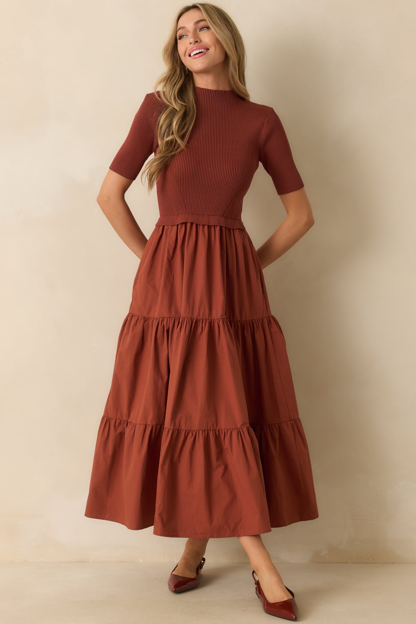 Rust red maxi dress with ribbed knit bodice, short sleeves, and tiered skirt falling to the floor.