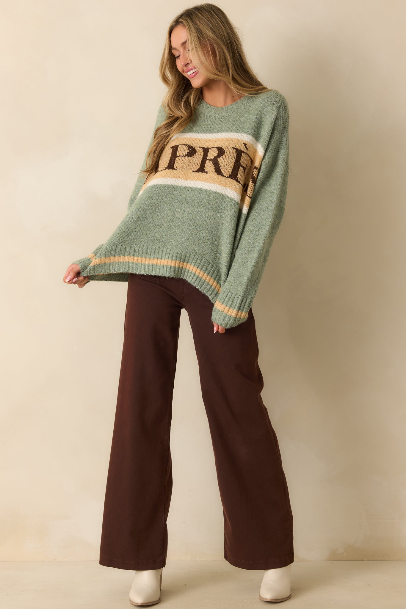 Sage green knit pullover sweater with long sleeves and ribbed trim, featuring contrasting tan and ivory stripes.