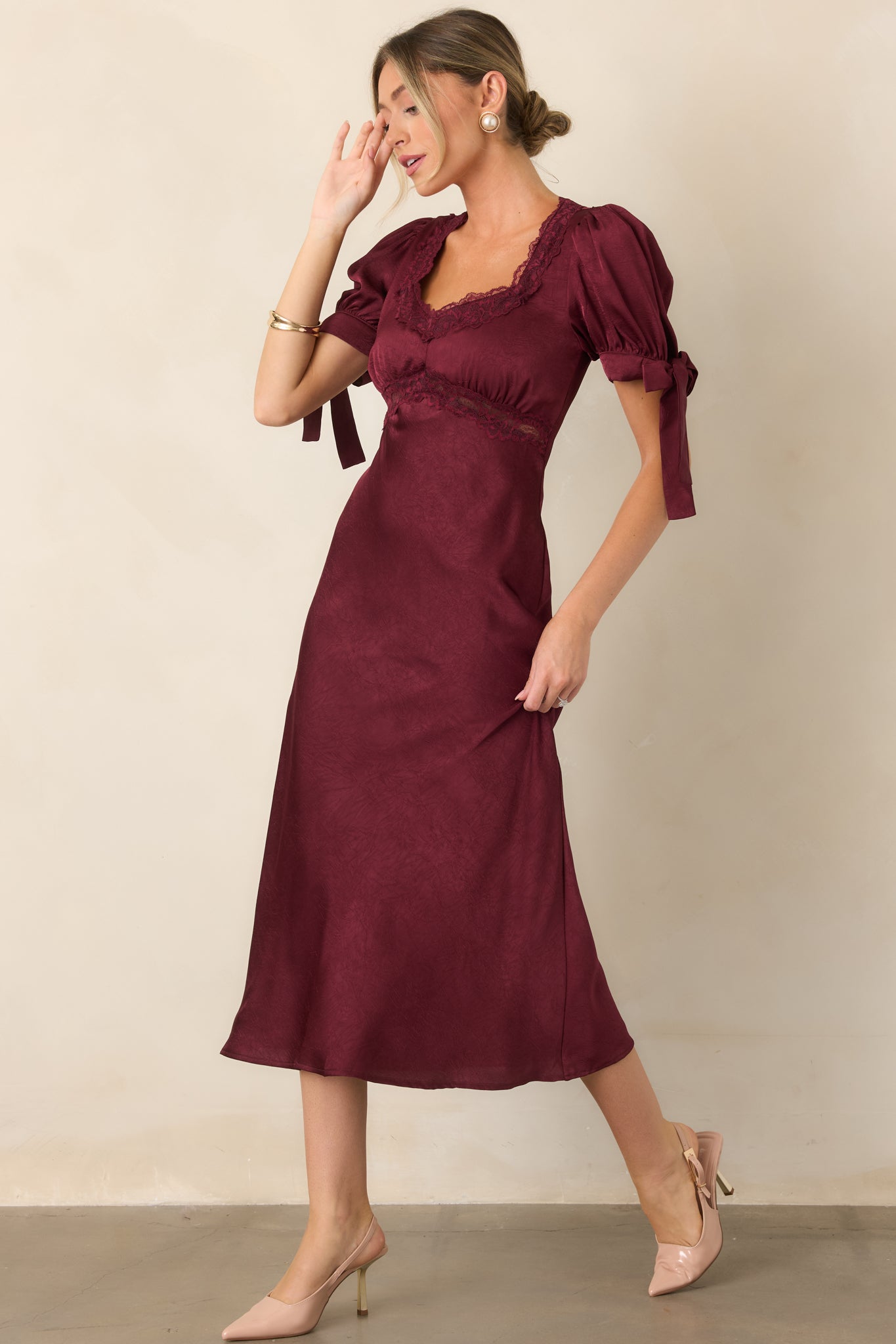Polished satin midi dress highlighting the contrast of delicate lace trim with short puff sleeves, self-tie cuffs, and a graceful empire silhouette.