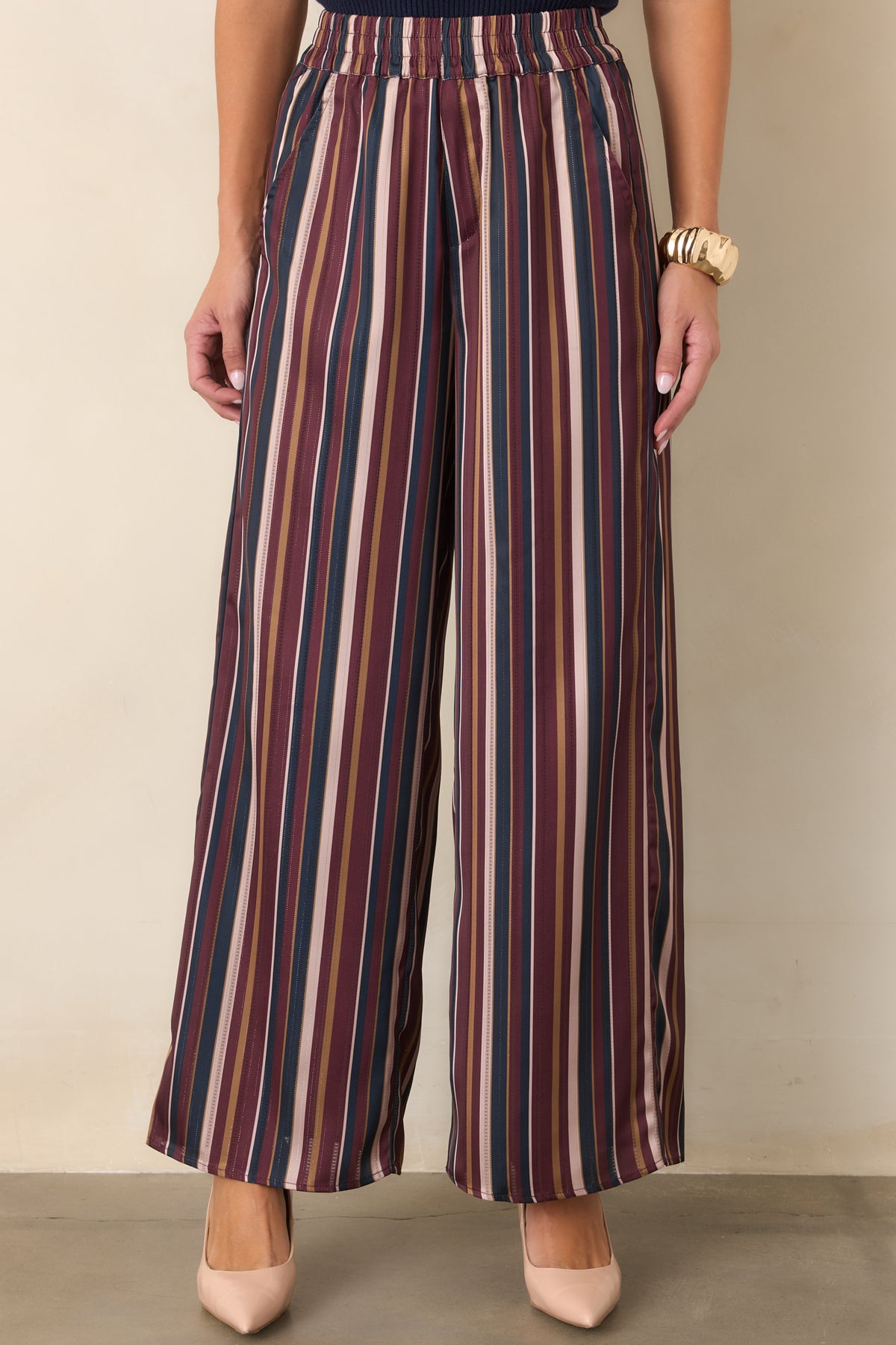 Satin pants highlighting the vertical burgundy, navy, champagne, and olive stripe pattern.