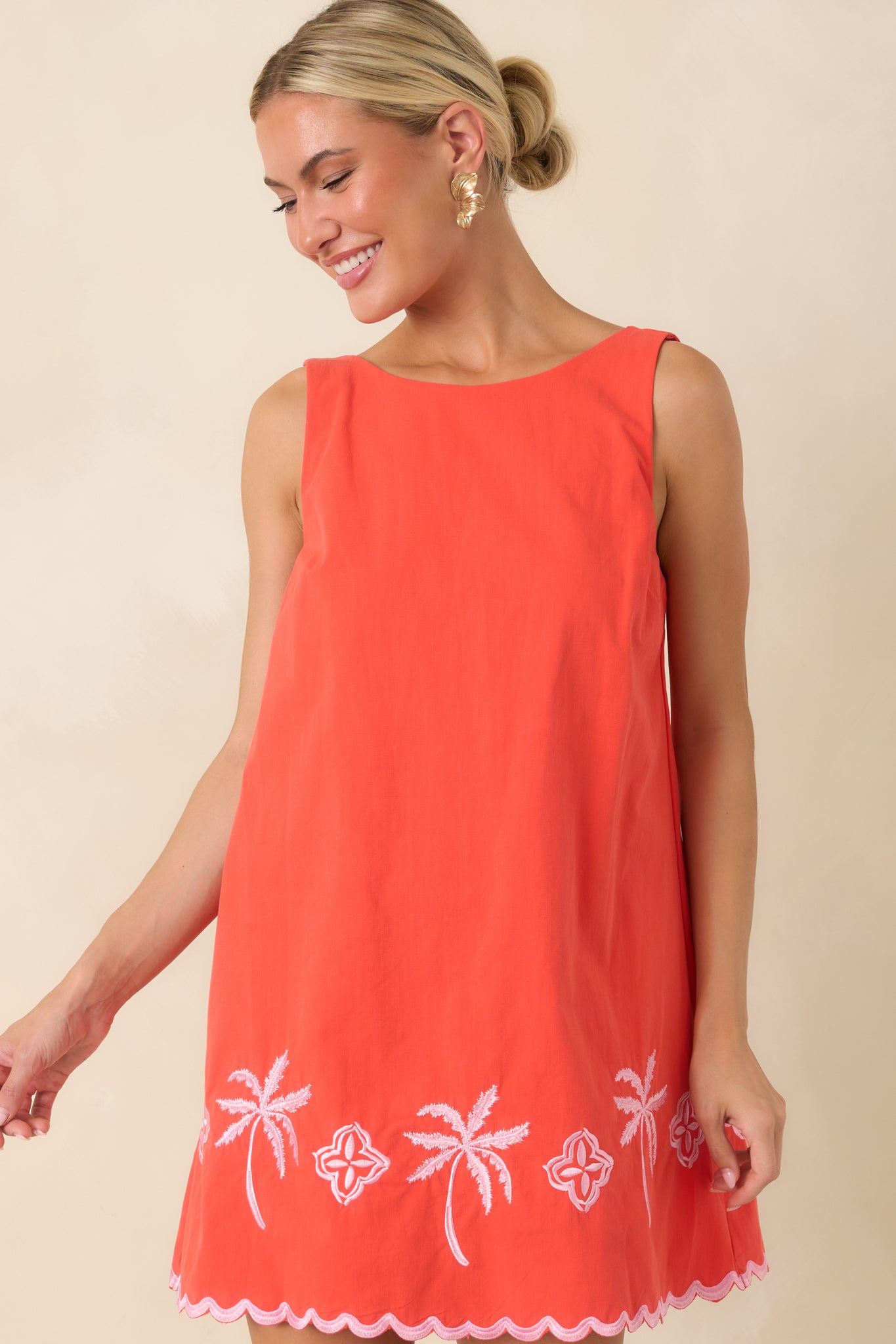Scalloped trim highlights the neckline and edges of this coral red embroidered cotton dress.