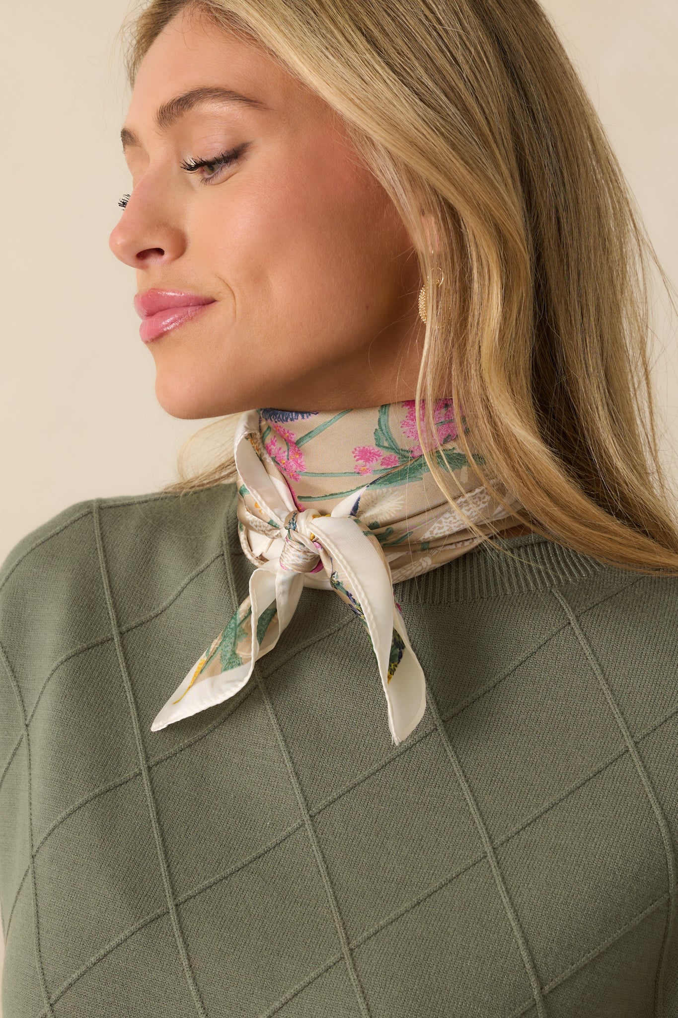 A view of the scarf shown tied around the neck, capturing a hint of the pink floral design and contrasting border.