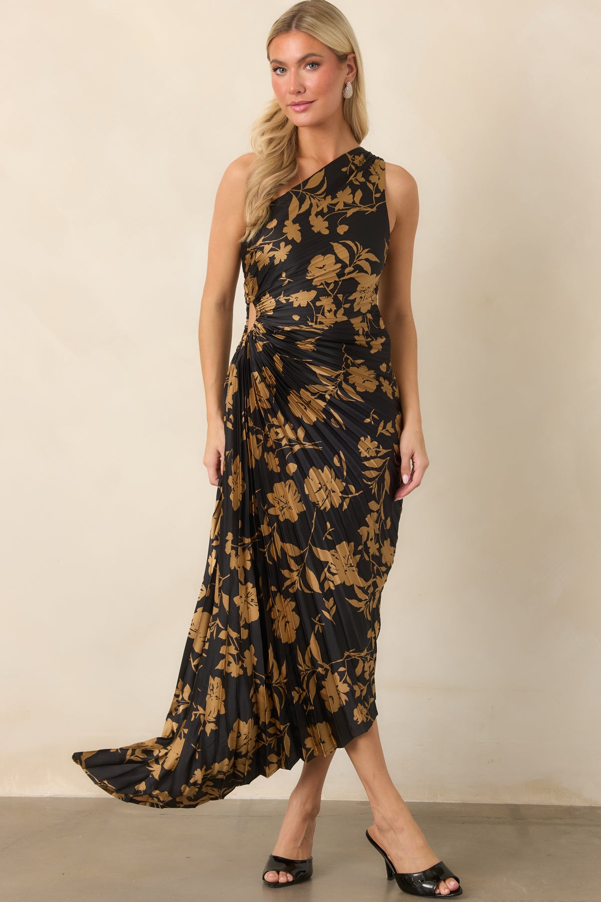 Sculpted pleating gives the black satin dress dimensional shape, while the golden floral pattern continues across the flowing skirt.