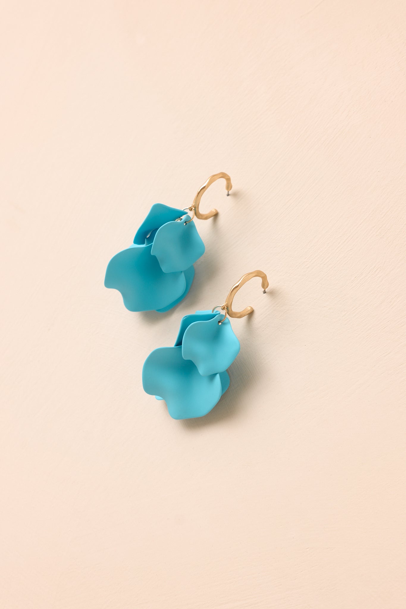 Gold-tone sculptural earrings with flowing petal details, textured hoops, and a contemporary matte finish.