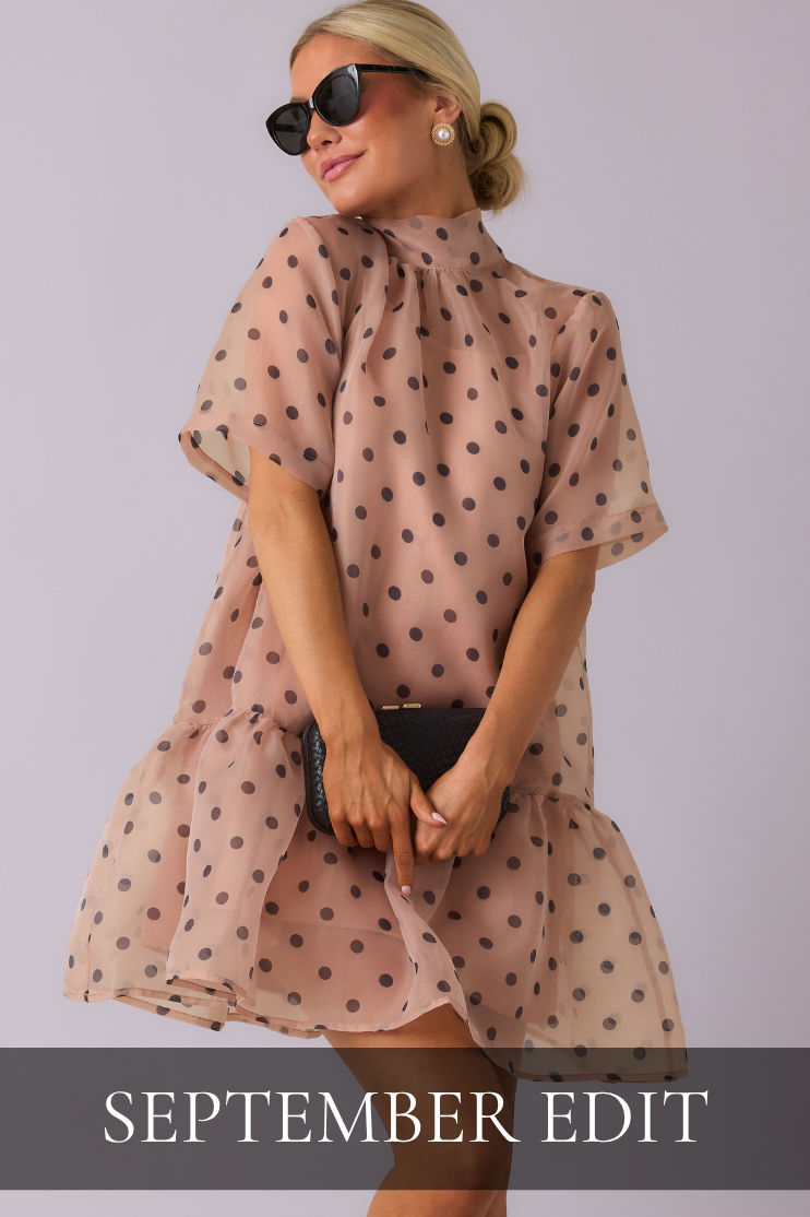 Model wearing beige mini dress with black polka dots. Dress is featured in the women's September Edit Collection.