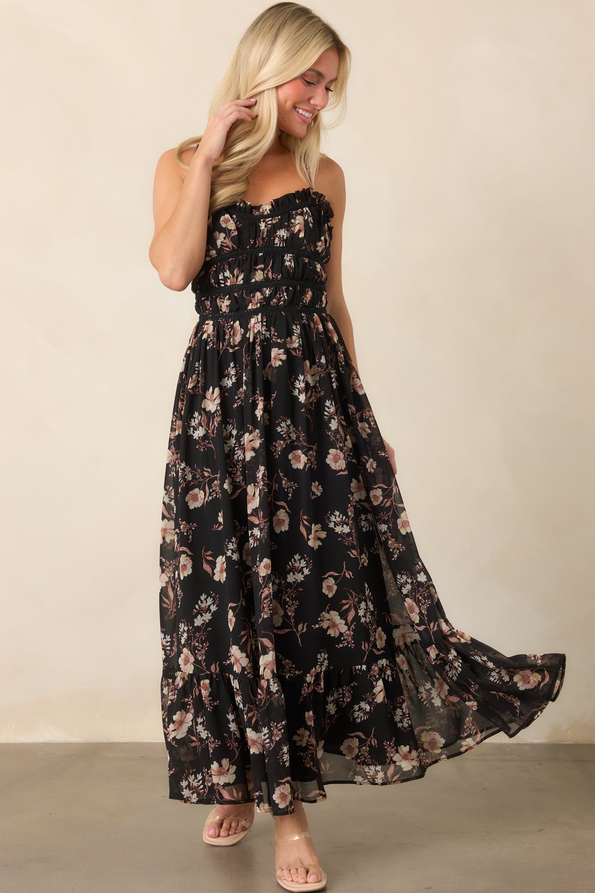 Sheer black dress with muted blush and ivory floral blooms, a gathered bodice, slender straps, and flowing ruffled hem.