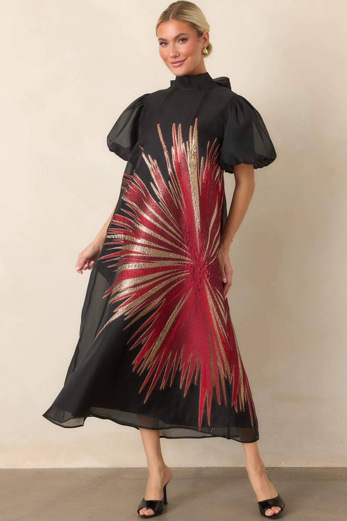 Sheer black dress showcasing the shimmering red and gold starburst design across the flowing A-line silhouette.