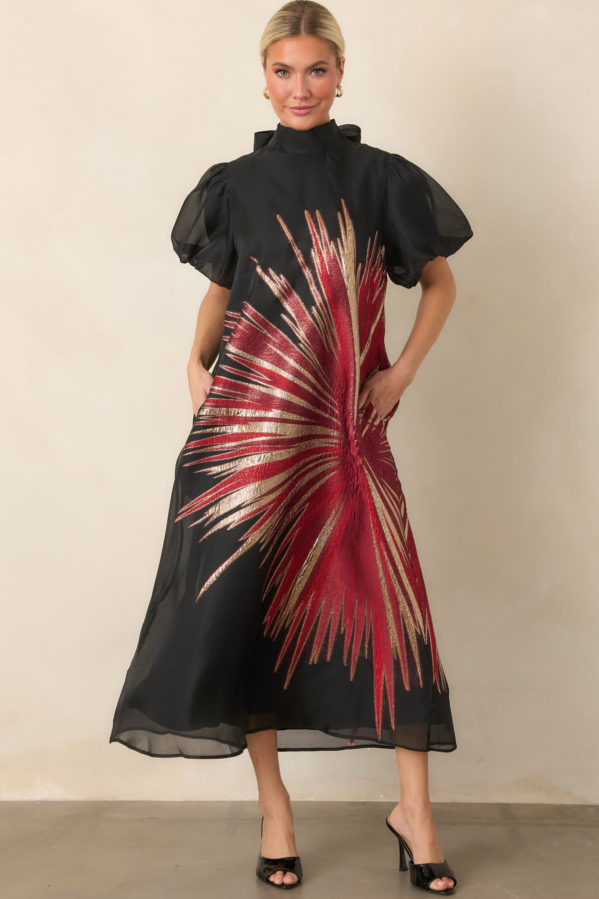Sheer black overlay dress featuring shimmering red and gold accents, a high neckline, and softly gathered puff sleeves.