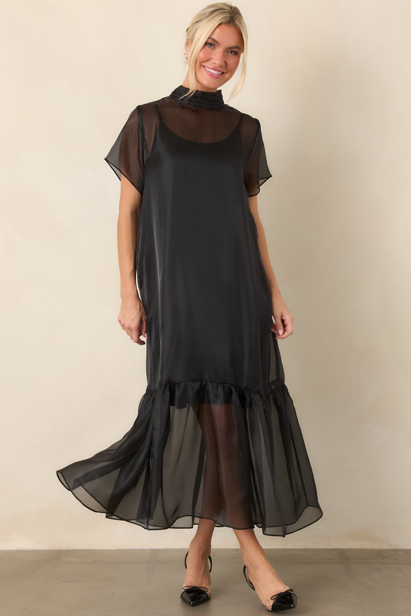 Ethereal maxi dress combining a sheer organza overlay with a smooth slip lining, delicate sleeves, and a flowing ruffled lower edge.