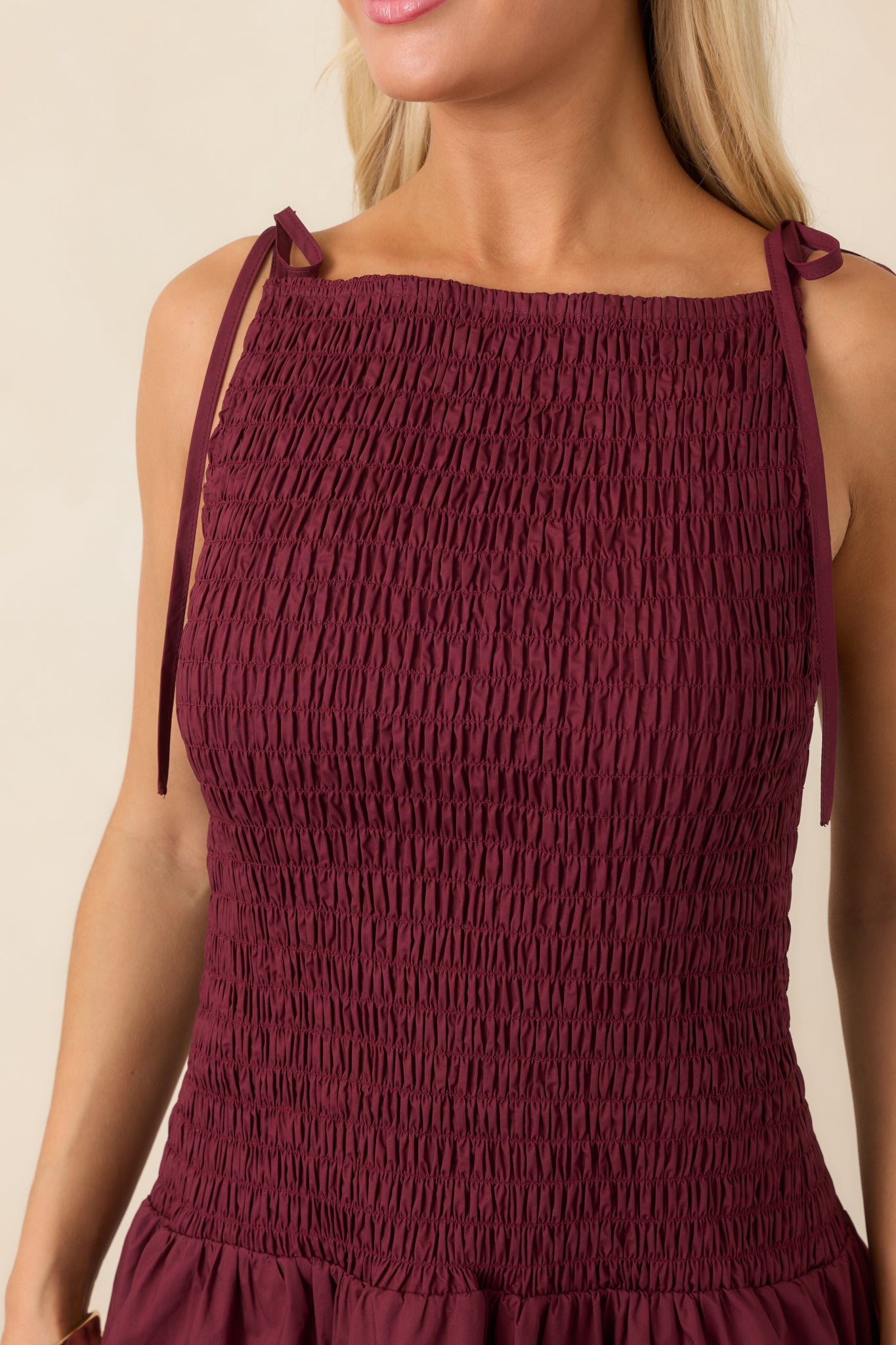 Close-up of the mini dress highlighting the intricate shirred texture, high neckline, and adjustable tie strap detailing.