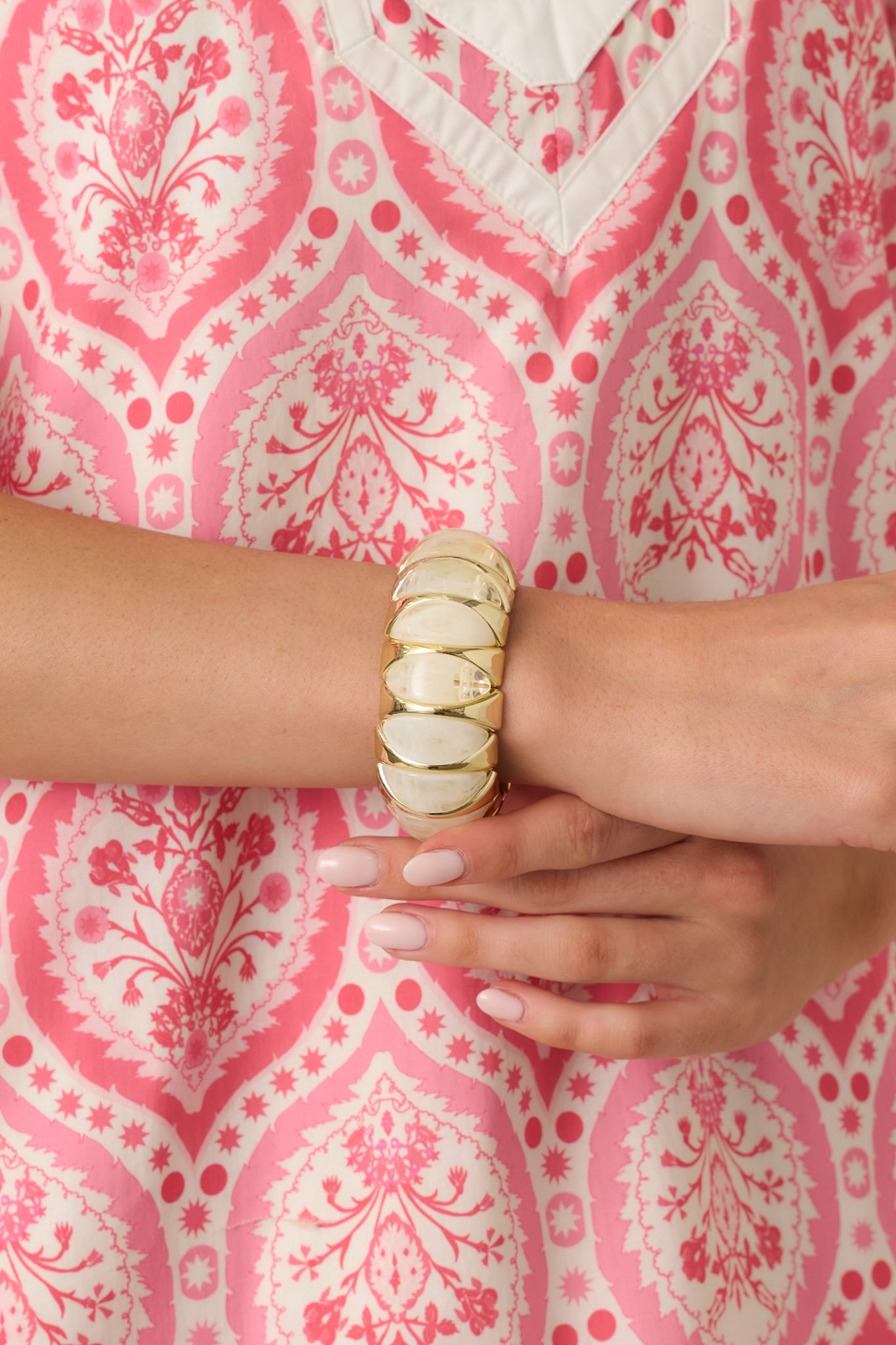 Close view of the white and clear marbled beads set within gold-tone settings on the stretch bracelet.