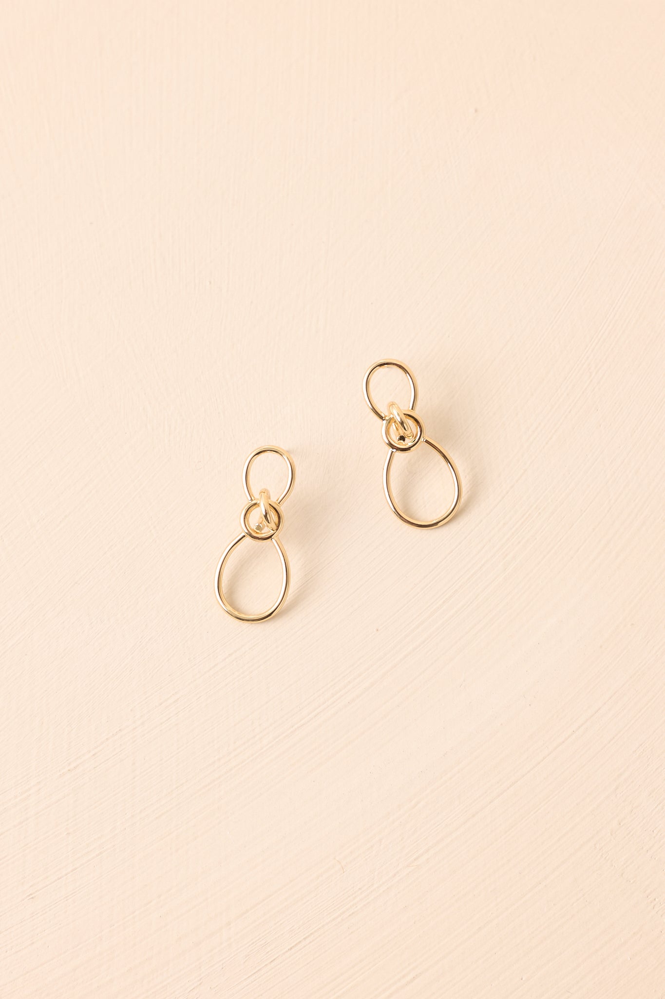A detailed shot of the oval interlocking gold earrings highlighting the layered hoops and shiny surface.