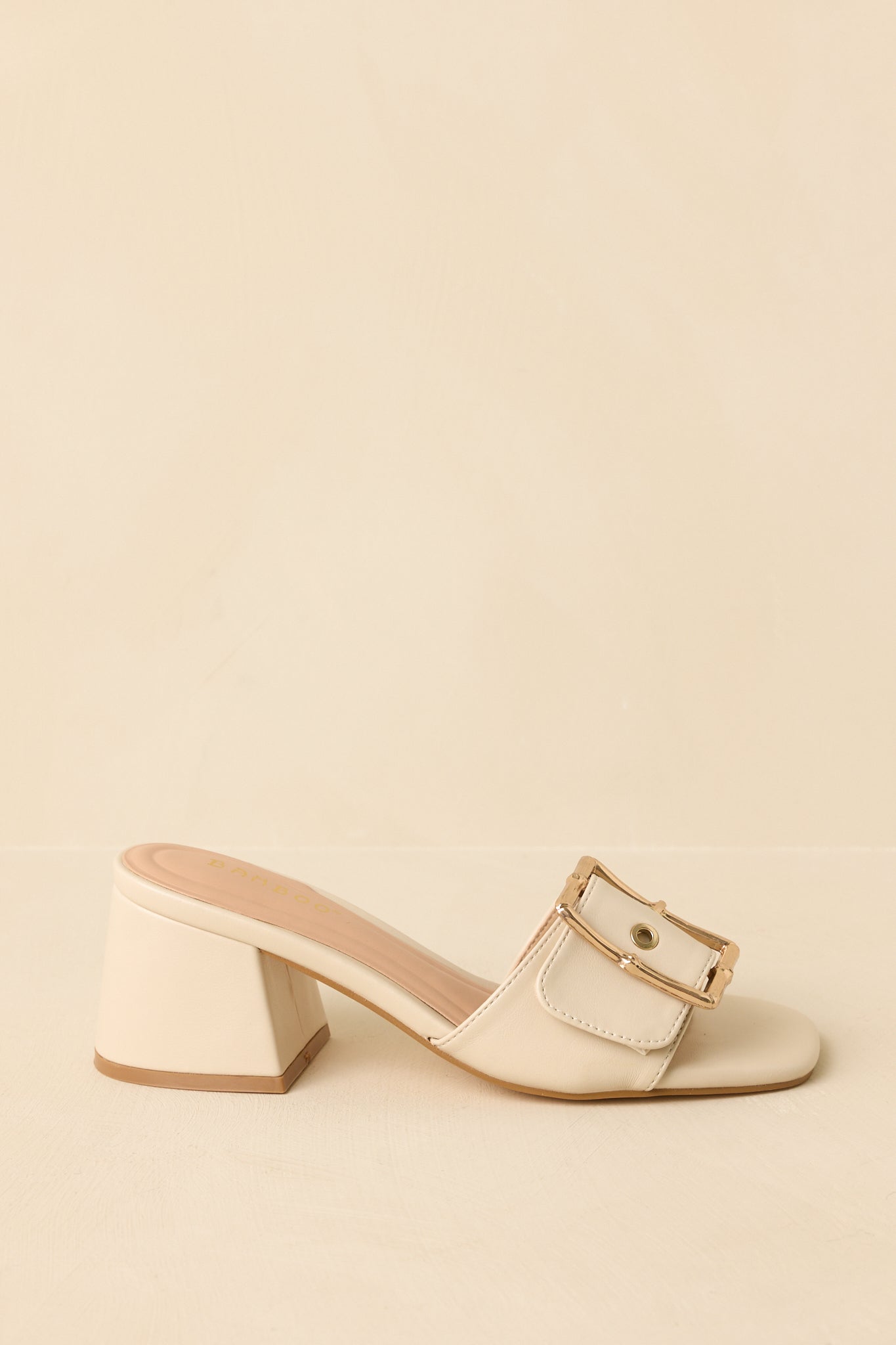 Side angle of the block heels against a beige background, emphasizing the height and shape of the sturdy heel.
