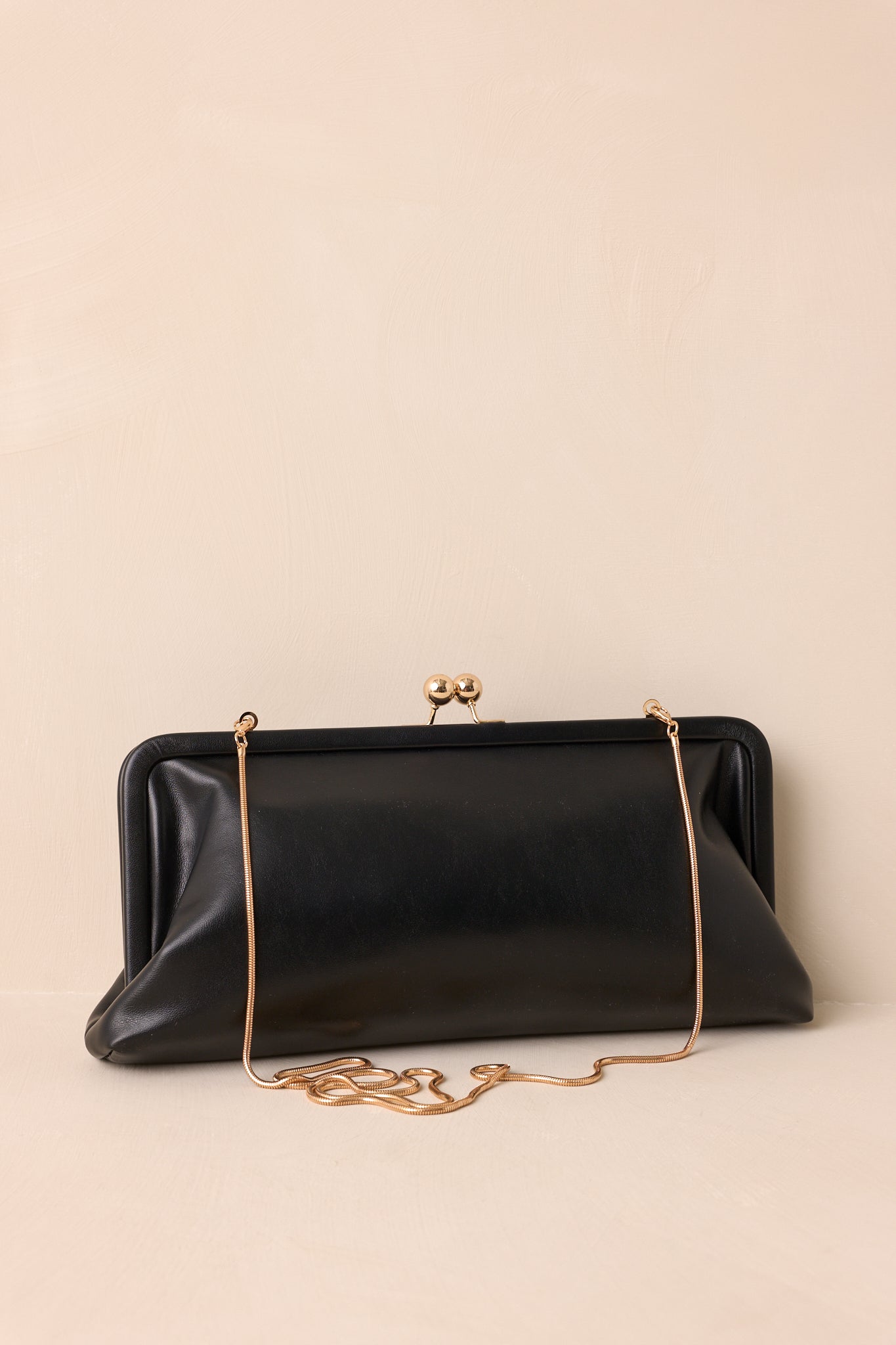 Side angle of the clutch highlighting the smooth faux leather exterior and structured shape.