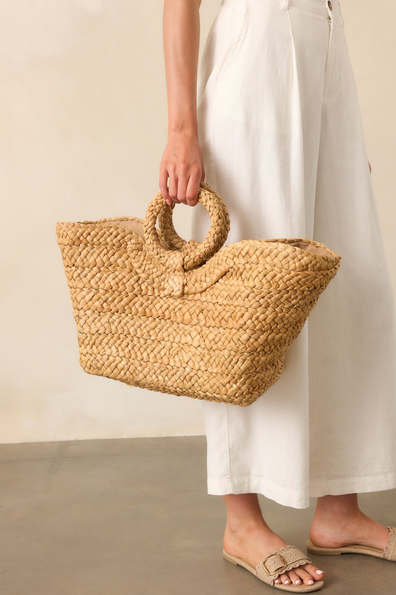 Side angle close-up of the tote emphasizing the depth of the open structure and raffia weave pattern.
