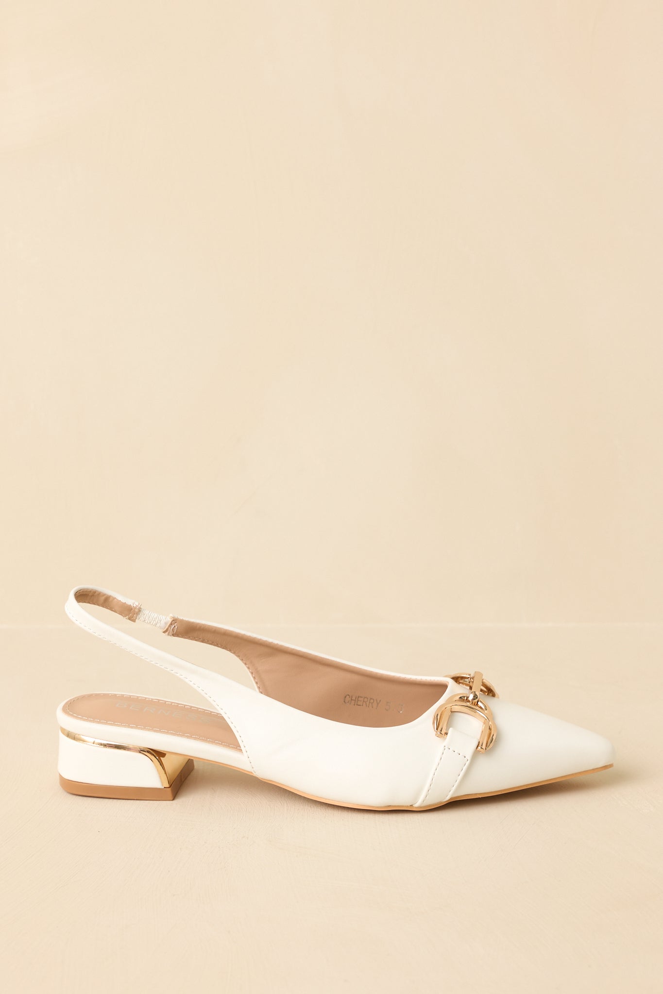 Side angle against a beige background emphasizing the slingback strap and pointed toe profile.