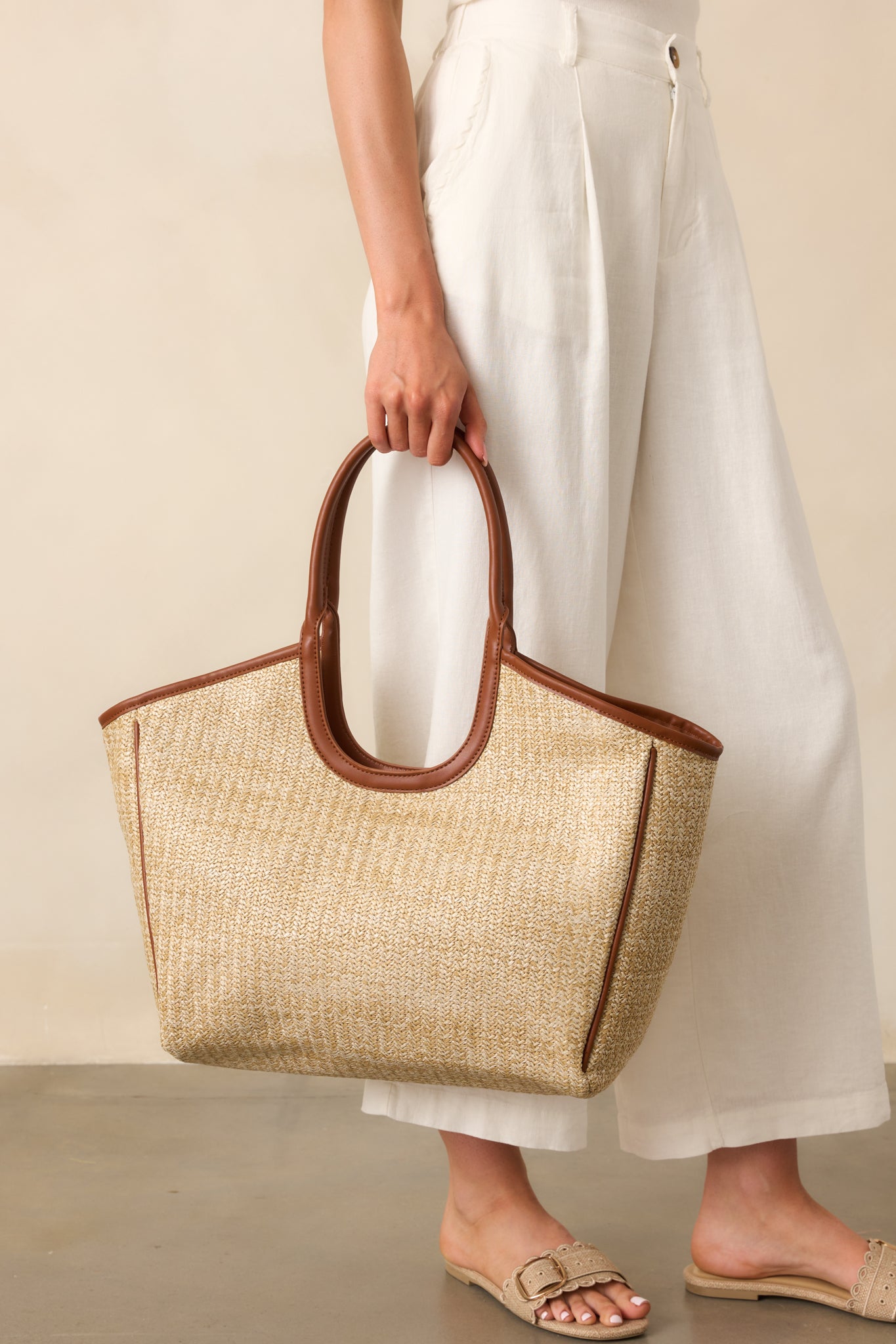 Side angle crop highlighting the structured edges and rich contrast between the rattan body and faux leather accents.