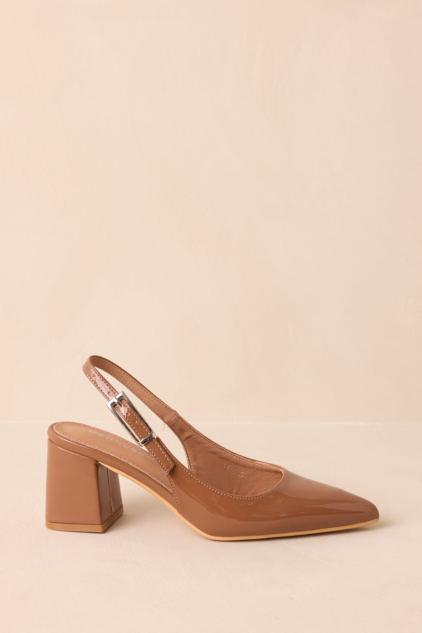 A side cropped angle of the heels showing the block heel and sleek patent body.