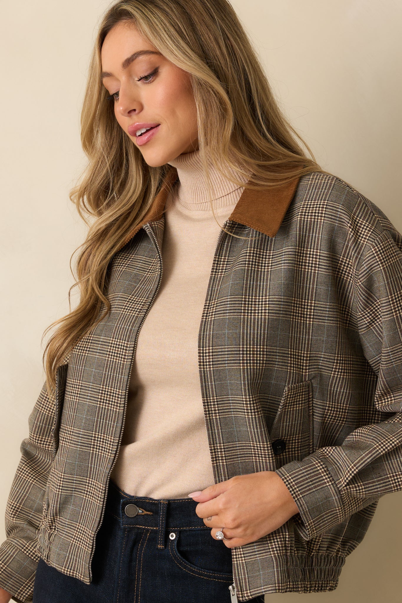 Side-focused shot showing the elastic hem and plaid pattern of the bomber jacket.