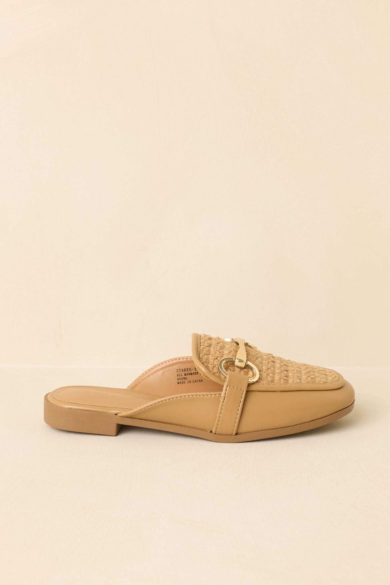 Side profile of tan mule loafers on beige background showing low heel and streamlined silhouette
