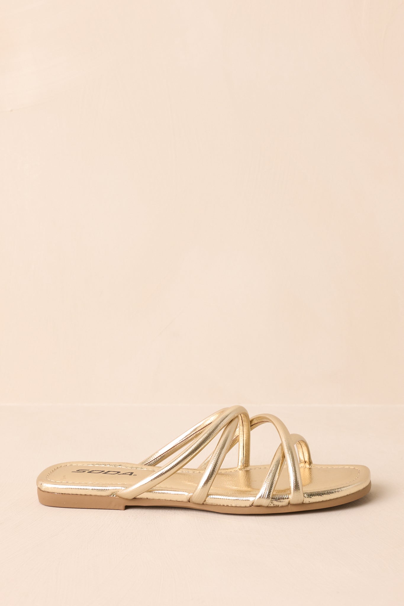 A complete side profile of the gold sandals, emphasizing the curve of the sole and strap placement.