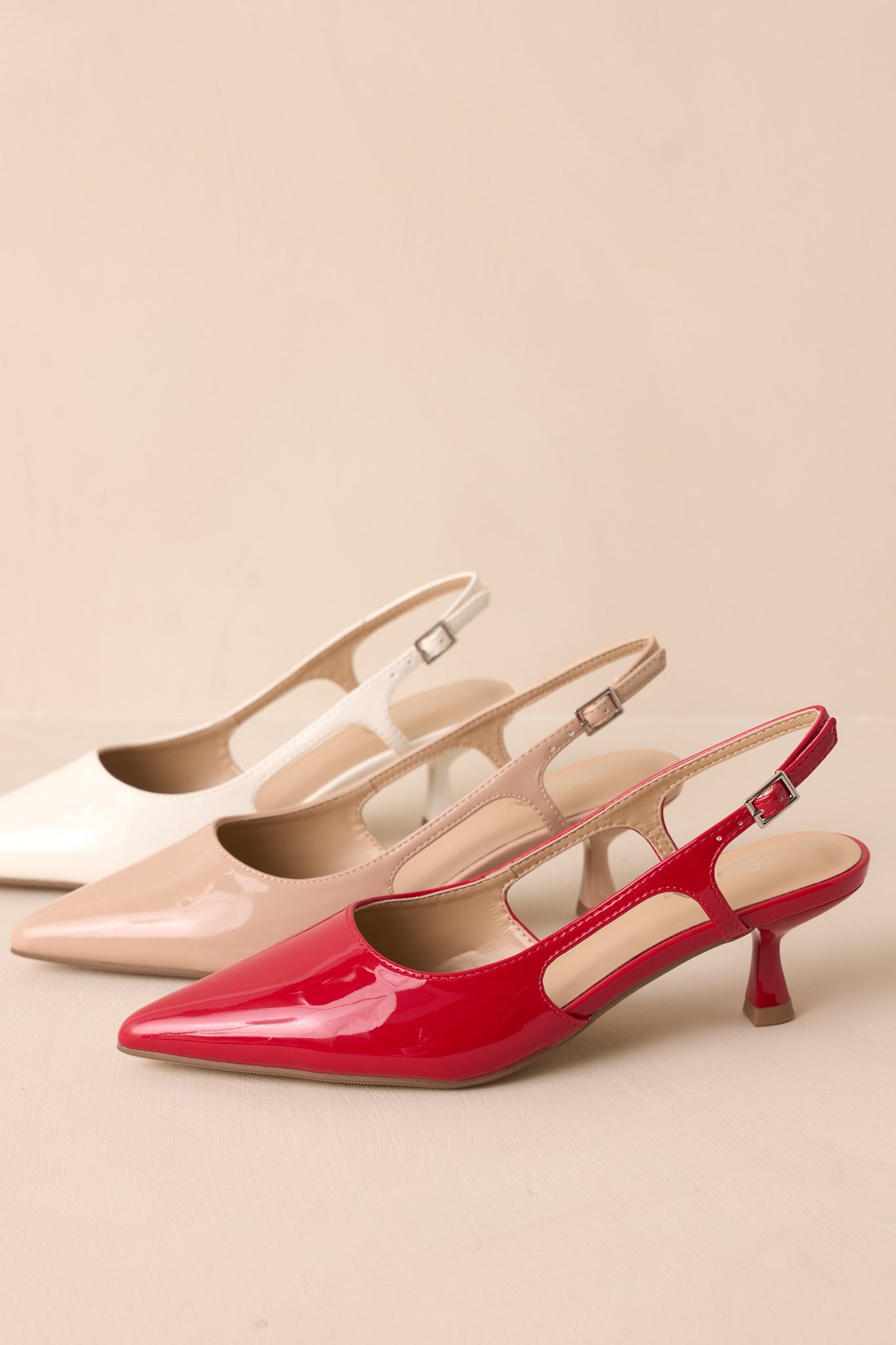 Side view of all of the slingback kitten heels highlighting the slim heel, cutout detail, and gold buckle accent.