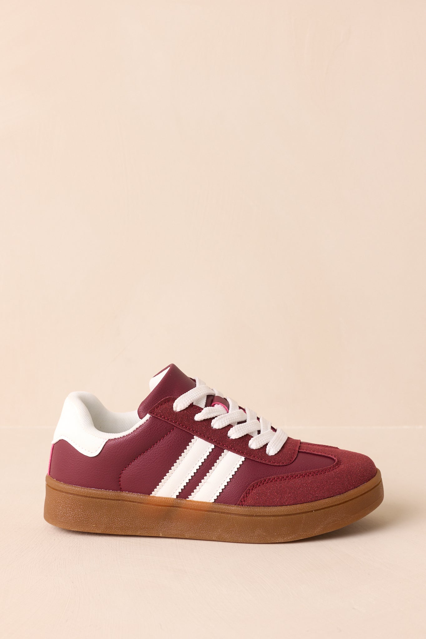 Side view of the burgundy faux suede sneaker with smooth synthetic panels, white contrast stripes, and a gum rubber sole.