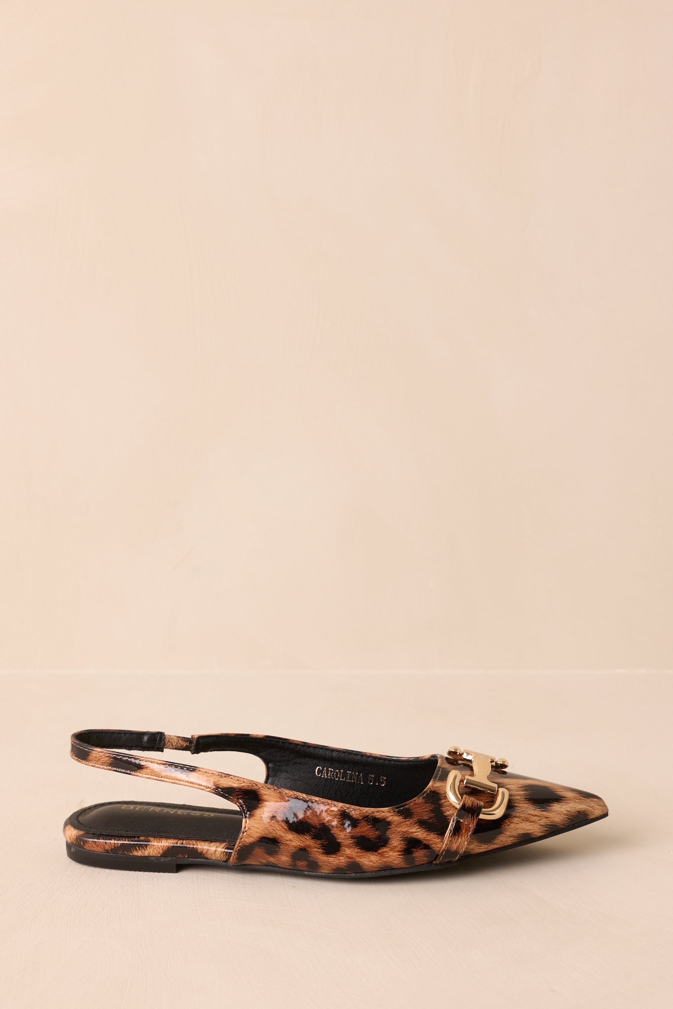 A side profile view of the flats against a beige background, emphasizing the elastic slingback and flat sole.