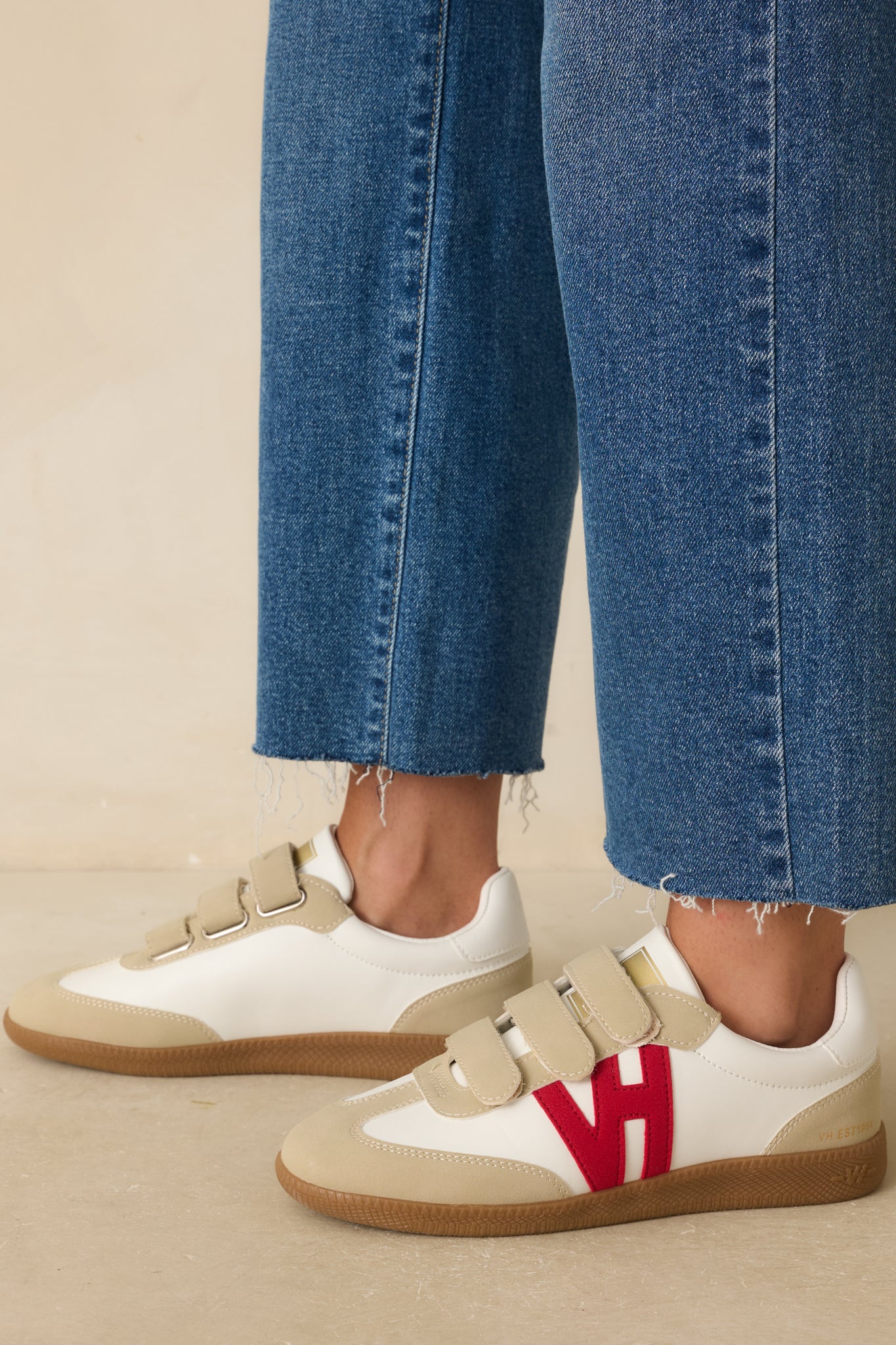 Side view of the sneakers highlighting the red faux suede side logo appliqué and gold logo detail on the tongue.