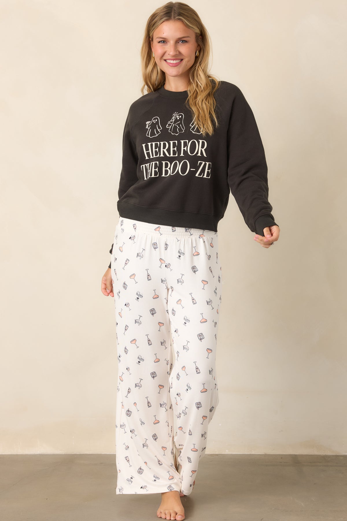 Silky ivory stretch pants with playful cocktail motifs, tiny spooky details, a pull-on smocked waistband, and softly draped wide legs.