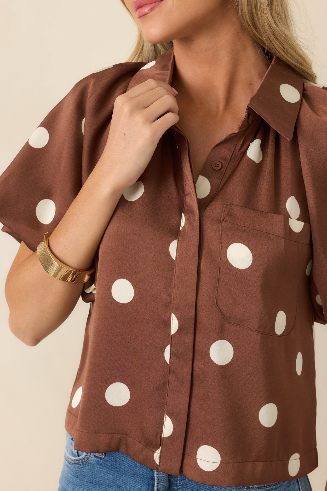 Close-up of the silky woven fabric displaying the ivory polka dots, concealed buttons, and smooth finish.