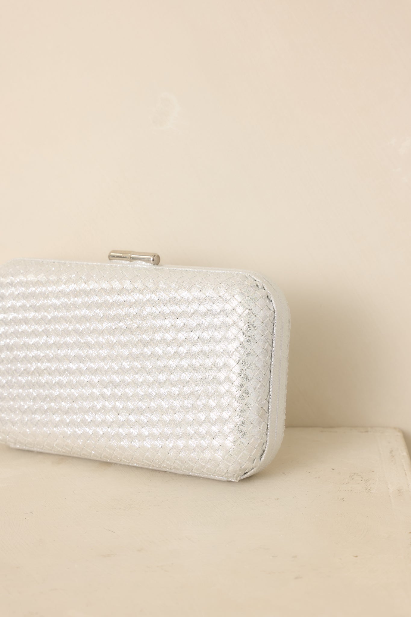 Close-up highlights the woven silver texture, rounded edges, hinged frame, and top clasp closure.