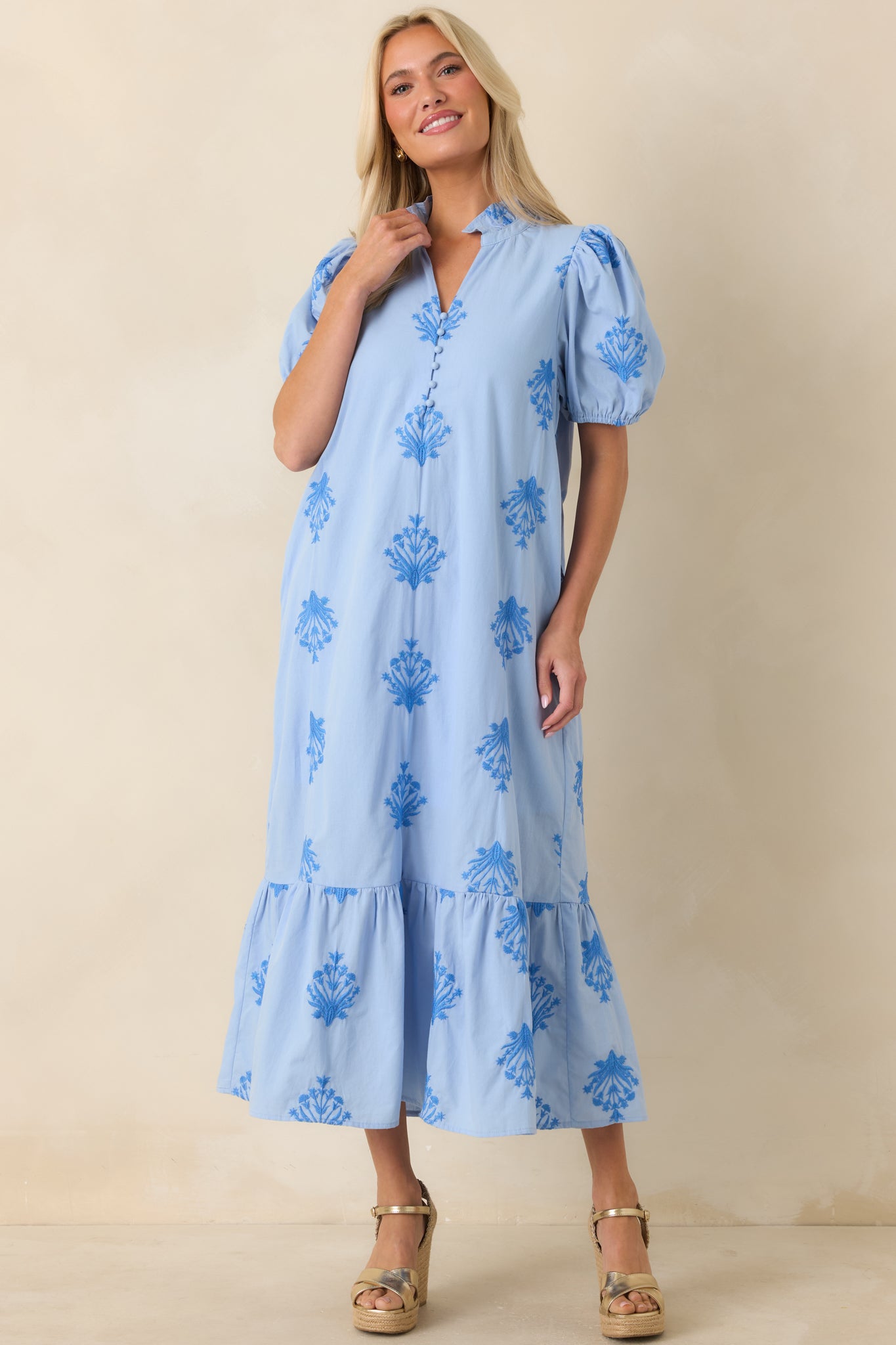 Sky blue cotton dress featuring allover tonal embroidery, puff sleeves, a split neckline with covered buttons, and a breezy silhouette finished with a ruffled hem.