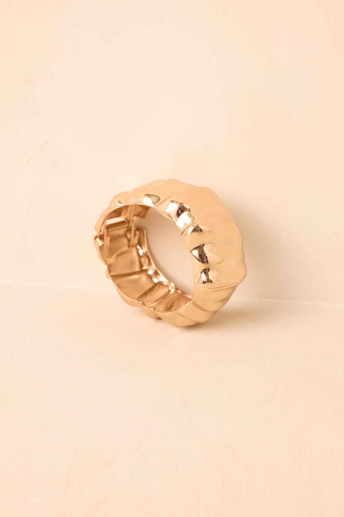 Sleek gold-tone cuff showcases a polished finish that catches the light across its smooth, statement-making silhouette.