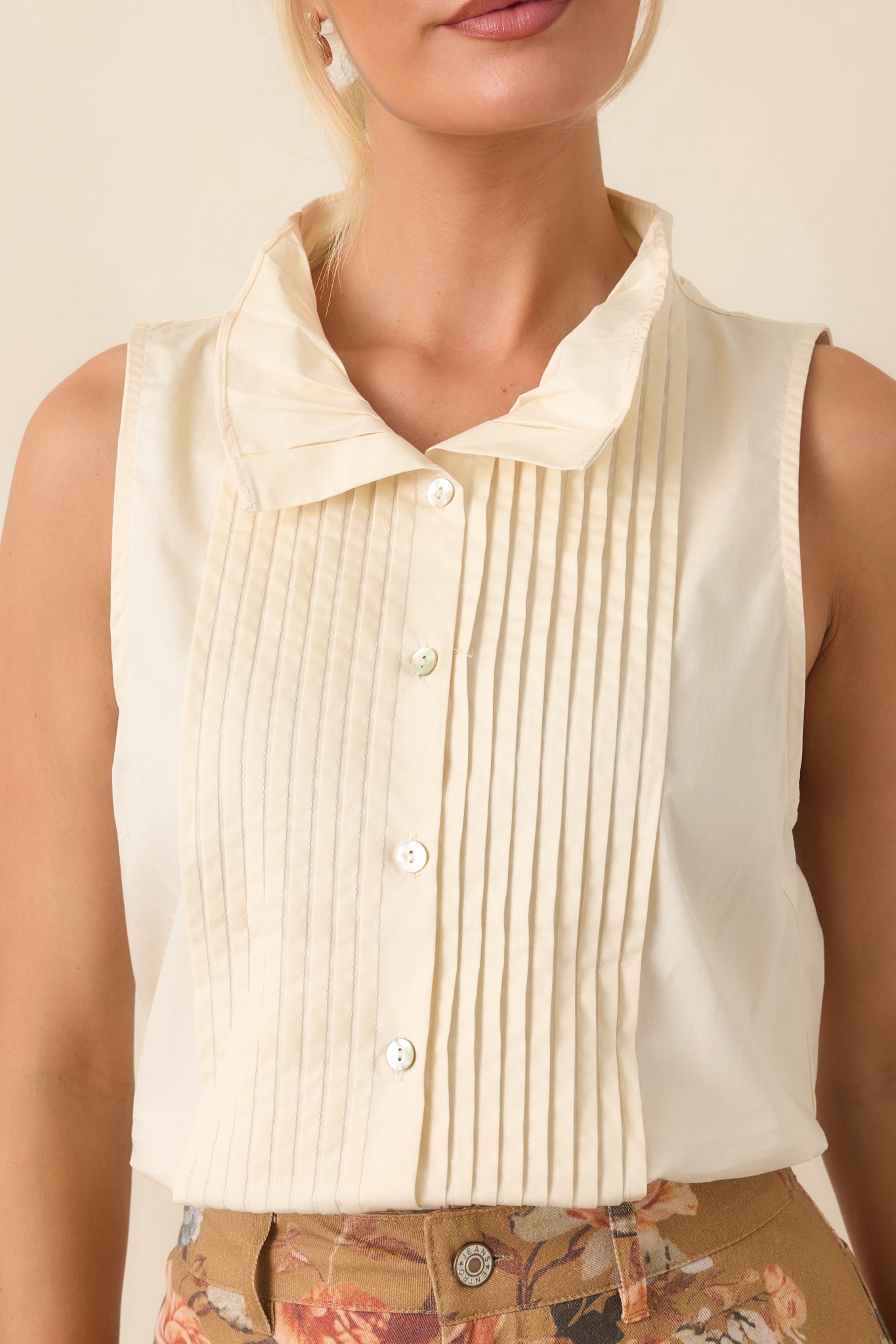 Close view of the sleeveless blouse showcasing its textured pleated design and refined collar construction.