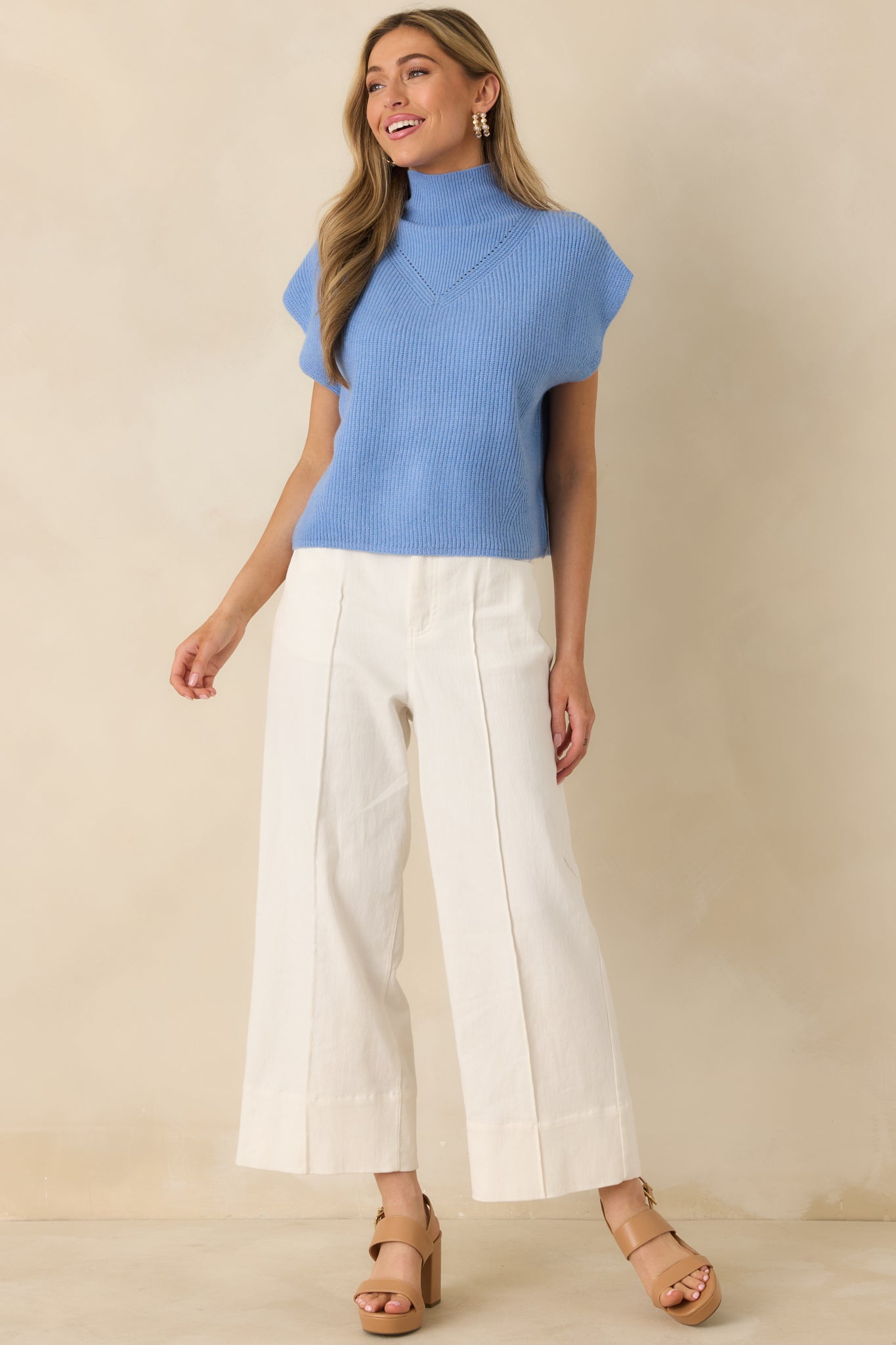 Sleeveless blue sweater top featuring subtle chest knit detailing, a clean hemline, and structured cap sleeve edges.