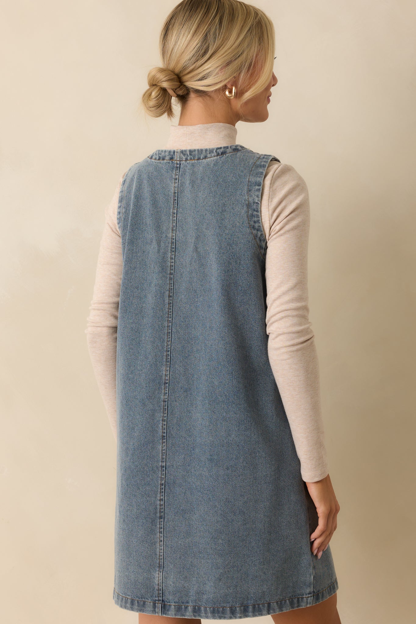 A back view of the sleeveless denim mini dress, showing the straight cut and medium-wash fabric.