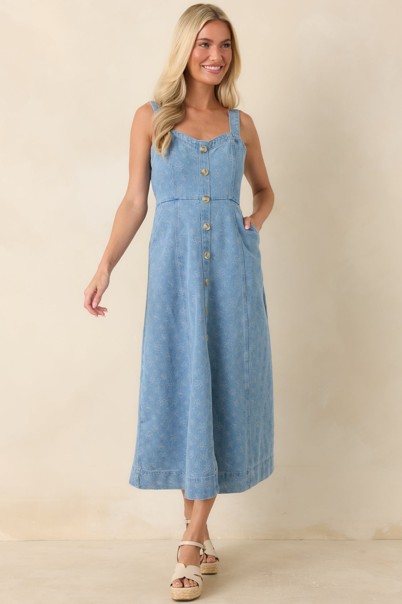 Sleeveless floral dress showcasing decorative front buttons, a fitted bodice, and flowing skirt shape.