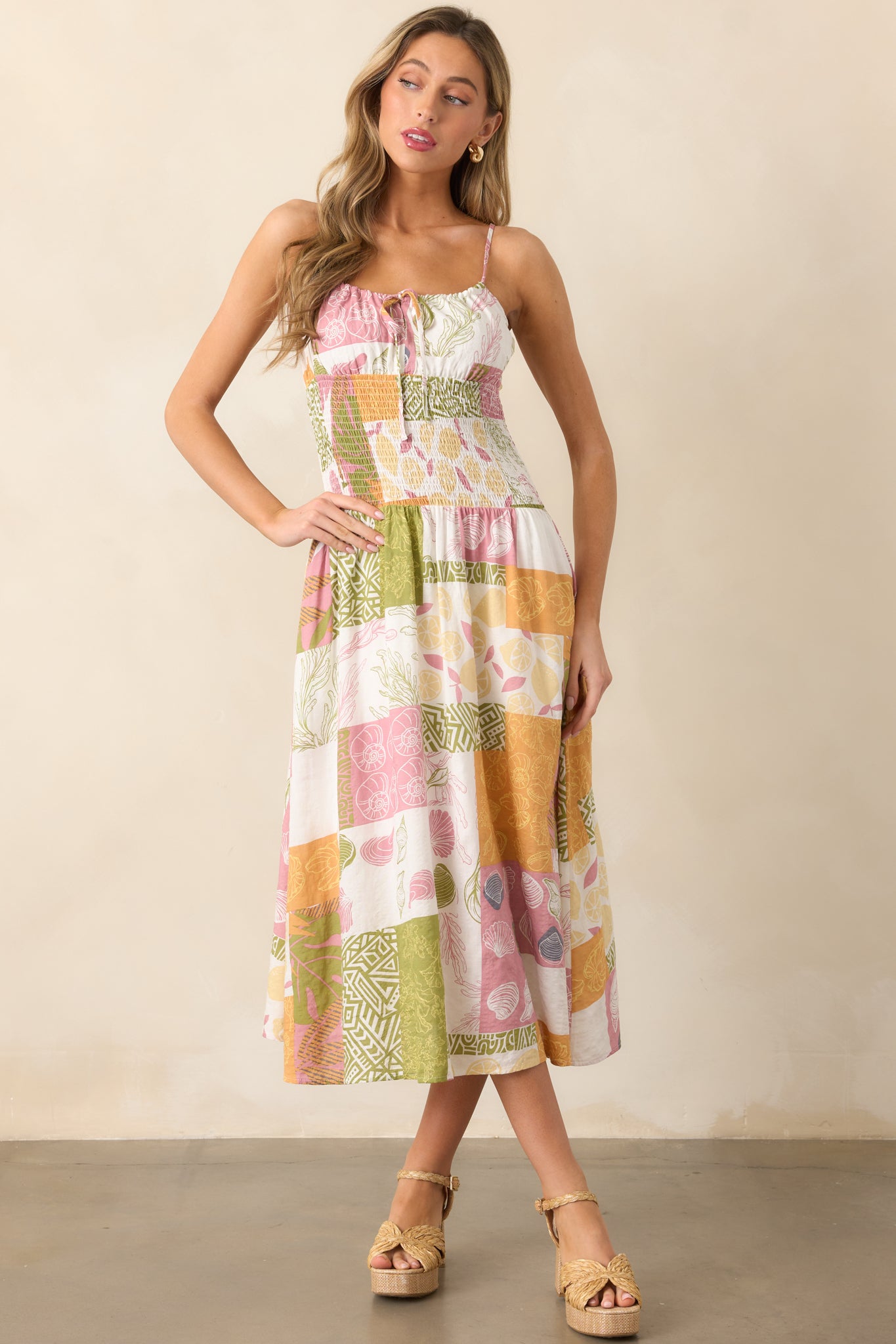 Sleeveless ivory dress with a self-tie neckline, featuring a tropical patchwork design and smocked waistband for a flattering fit.