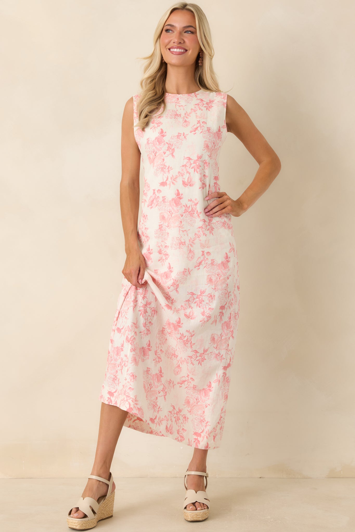 Sleeveless ivory maxi dress adorned with a soft pink floral pattern, showcasing a relaxed shape and graceful floor-grazing length.