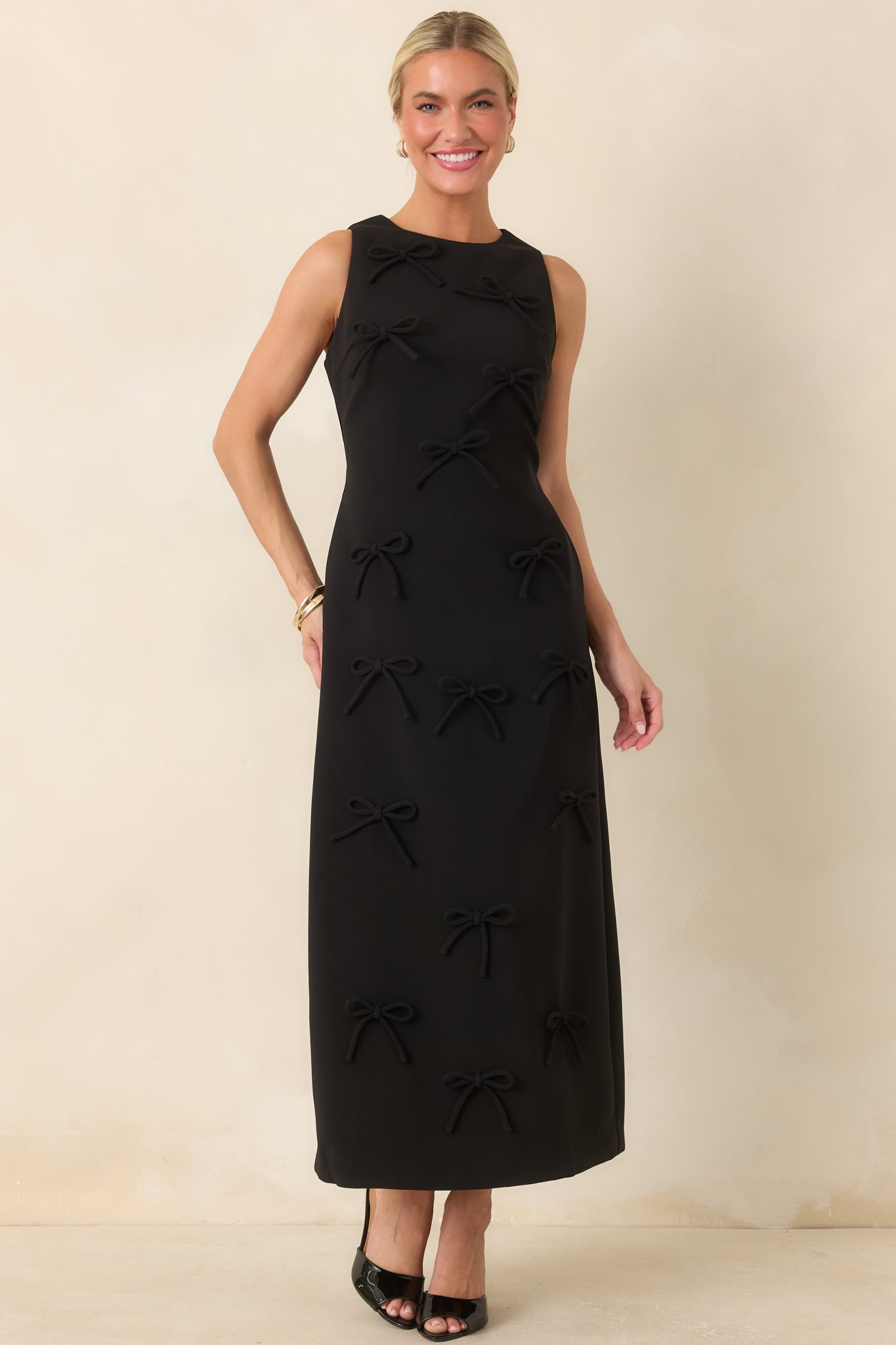 Sleeveless maxi dress with strategic seaming, a streamlined silhouette, and playful dimensional bow accents.