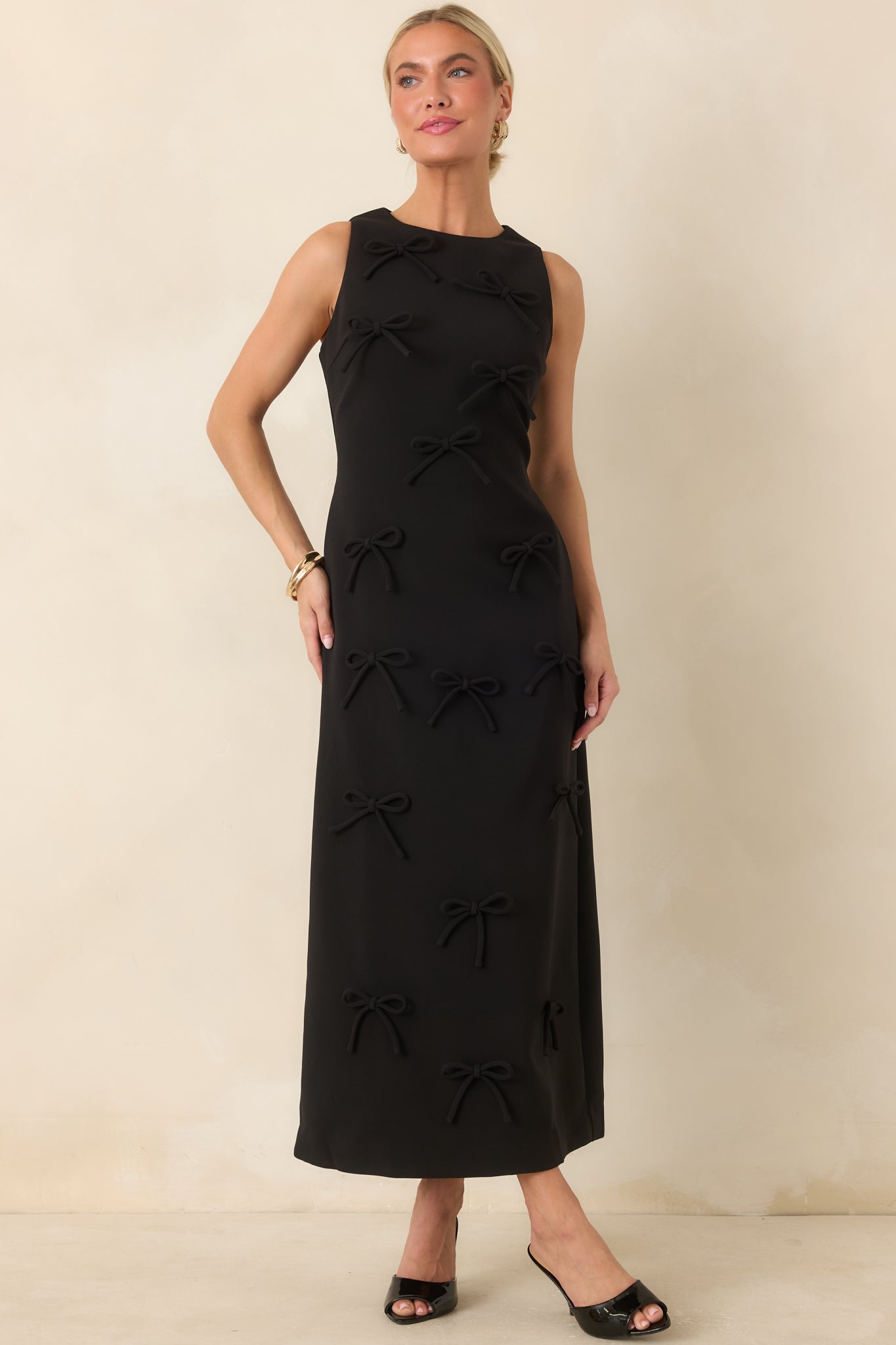 Sleeveless maxi dress featuring a round neckline, column silhouette, and tonal three-dimensional bow embellishments.