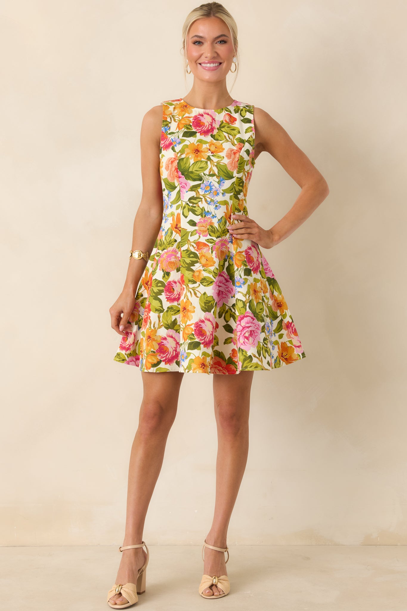 Sleeveless ivory mini dress featuring colorful floral pattern and structured seams, with a twirl-ready silhouette.