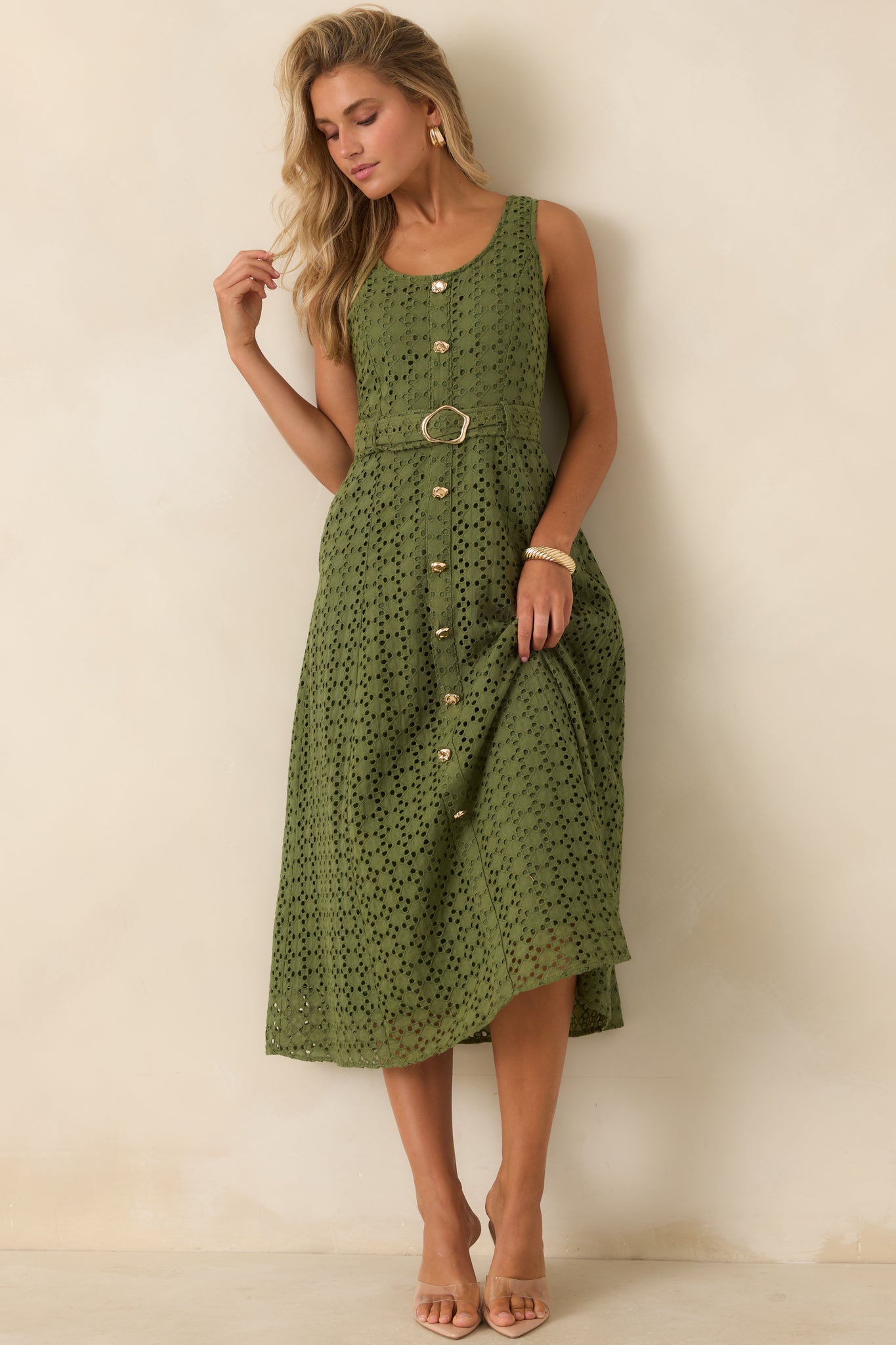 Sleeveless olive green midi dress showcasing detailed eyelet embroidery, functional side pockets, and a feminine belted silhouette.