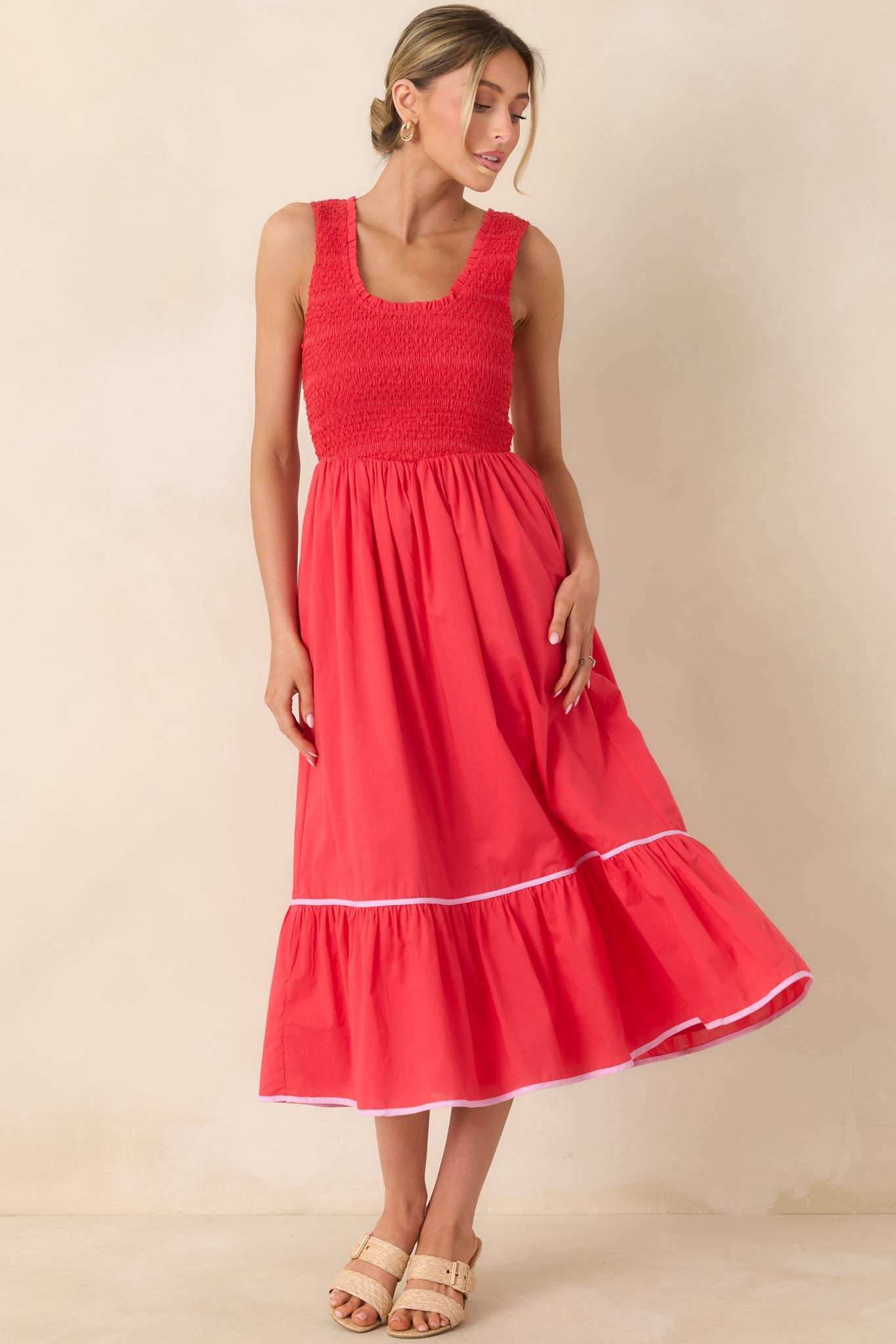 Sleeveless red cotton dress designed with a flattering scoop neckline and flowing tiered silhouette.