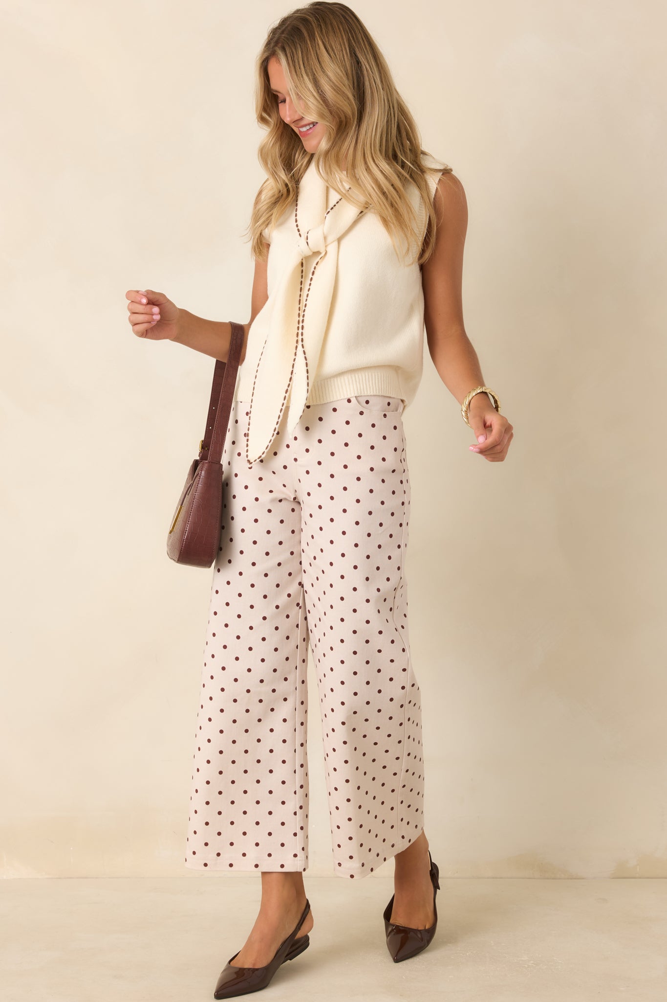 Sleeveless knit sweater designed with a draped scarf collar, elegant tie detail, and polished ribbed edges.