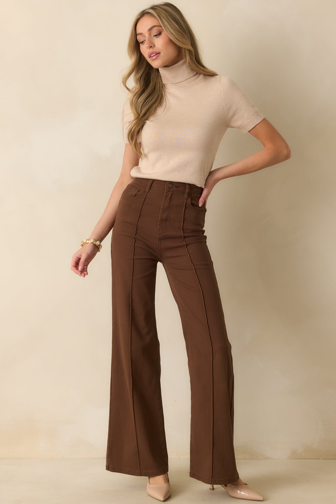 Slightly fitted beige knit top with rolled turtleneck and soft ribbed fabric finish.