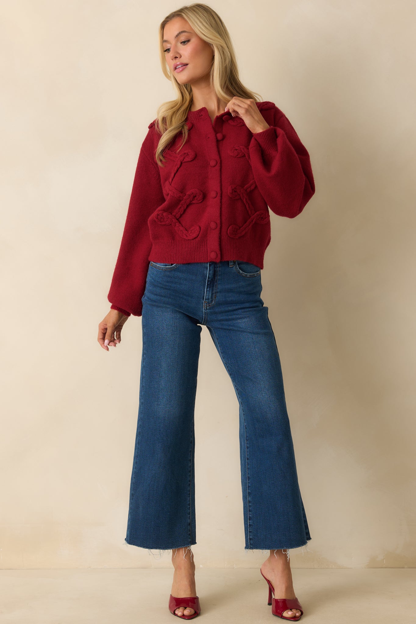 Slim-fit red knit cardigan showcasing front button closures, braided appliqué, and round neckline.