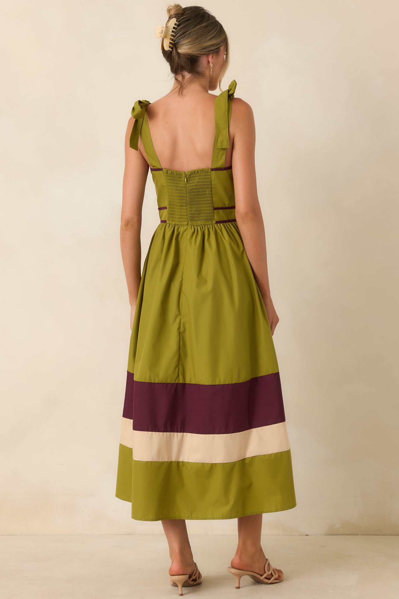 Rear view of the midi dress featuring a smocked back, adjustable tie straps, and flowing gathered skirt.