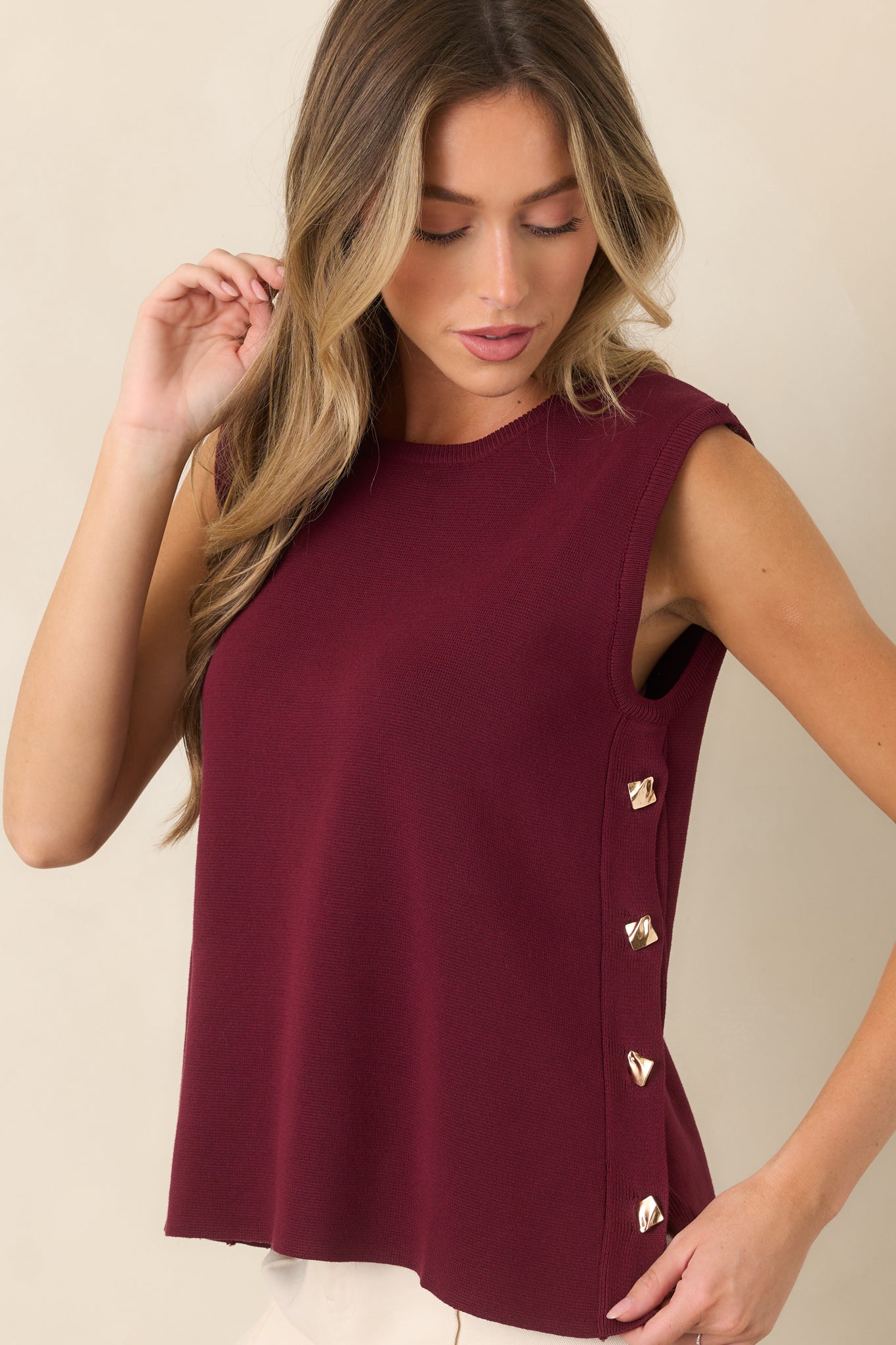 Sleeveless sweater detail emphasizing the fluid drape and smooth breathable knit fabric alongside the modern side-button accent.